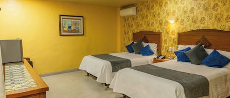 Habitación de hotel con dos camas, un escritorio y un cuadro en la pared.