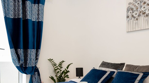 Een keurig opgemaakt bed met een blauw dekbed, een dienblad met ontbijtartikelen en bijpassende kussens.