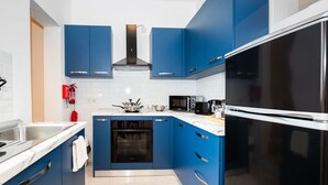Een moderne keuken met blauwe kastjes, een roestvrijstalen spoelbak, een ingebouwde oven, een magnetron en een koelkast.