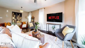 A modern living room with a flat-screen TV, comfortable seating, and a ceiling fan. - 4BDRM Chic Home - King Bed - BBQ - Garage - WiFi (Edmonton)