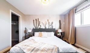 Ein Schlafzimmer mit einem großen Bett, einem Kleiderschrank und einer Wanddekoration mit Kakteen.