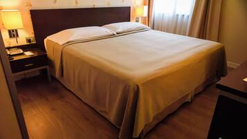 Una habitación de hotel con cama, mesita de noche, lámpara y teléfono.