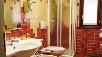 Une salle de bain équipée d’une douche, de toilettes, d’un bidet et d’un lavabo.