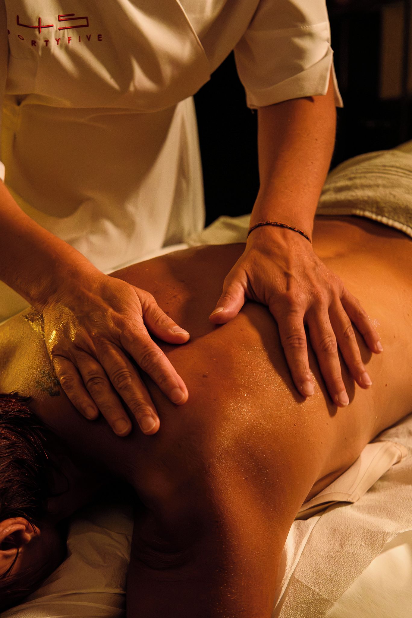 Eine Person erhält eine Massage, wobei der Fokus auf Händen und Rücken liegt.
