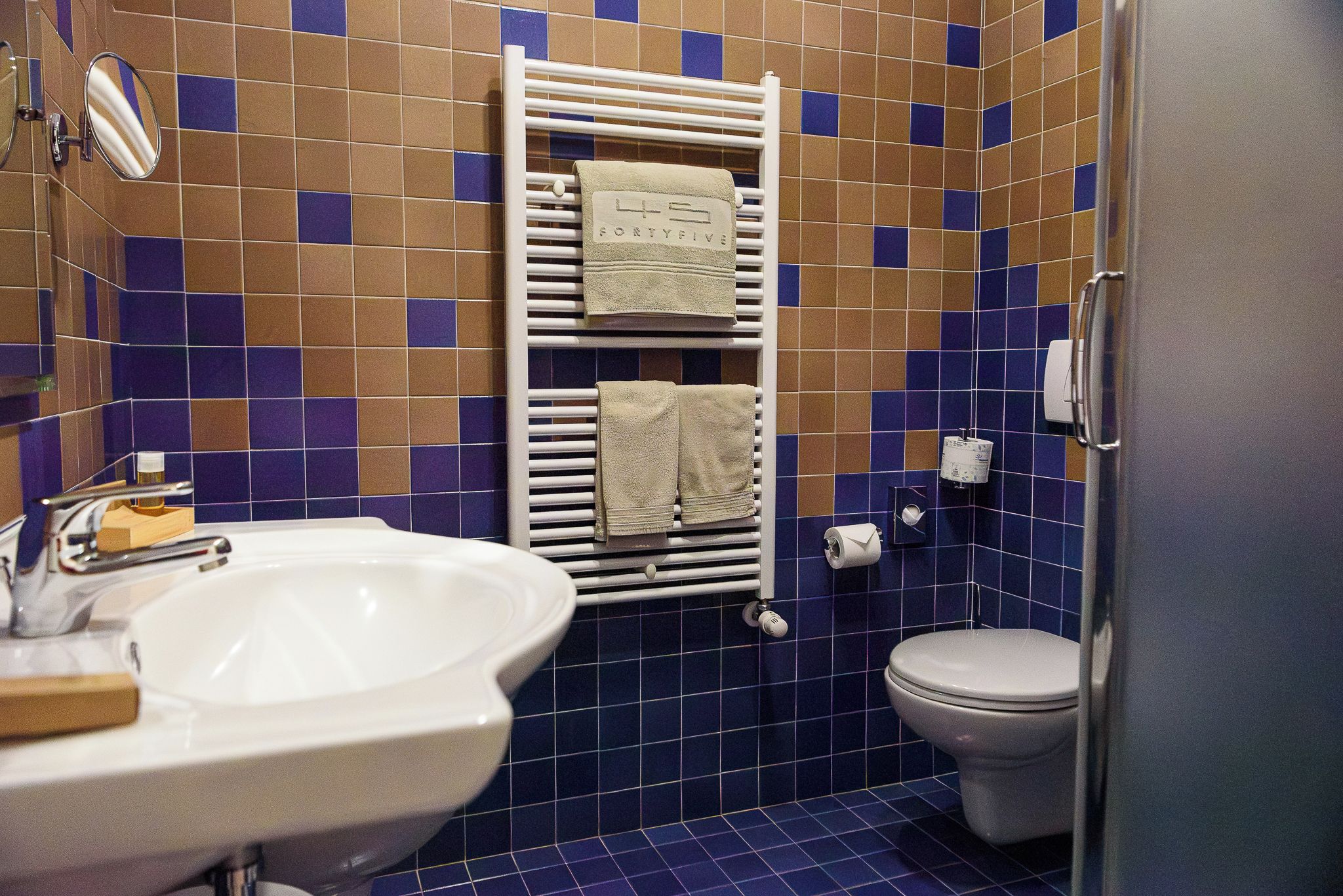 A bathroom with a white sink, a toilet, and a towel rack with folded towels.