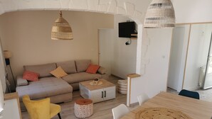 A modern living room with a sofa, ottoman, and a wooden dining table with chairs. - Maison à 5 Minutes de la Plage, la Chicane, Laiguillon sur Mer (L'Aiguillon-la-Presqu'île)