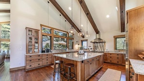A spacious kitchen with wooden cabinets, a large island, and pendant lighting.