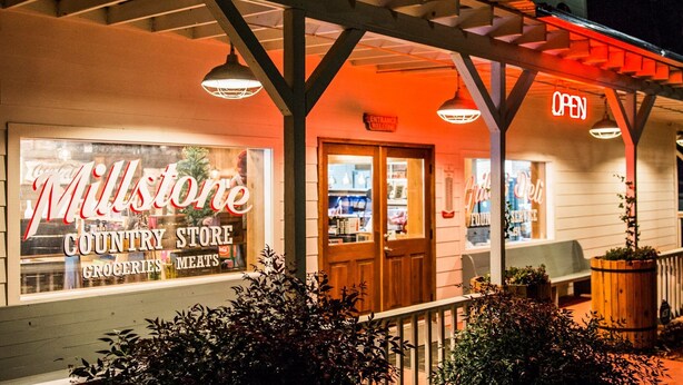 Maaseutukauppa, jonka yläpuolella on kyltti, jossa lukee ”Millstone Country Store”, ja sisäänkäynnin yläpuolella on kyltti, jossa lukee ”AVOINNA”.
