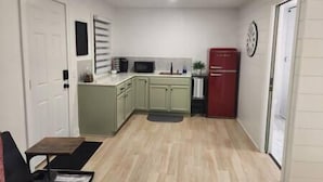 A compact kitchen with a microwave, sink, and red refrigerator. - Cozy Nook Cottage With Hot Tub (Nevada)