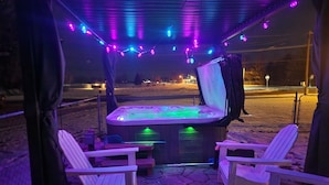 An outdoor hot tub area with seating and string lights. - Cozy Nook Cottage With Hot Tub (Nevada)