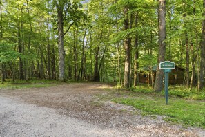 Een bebost gebied met een grindpad dat naar een chalet leidt, aangeduid met 'BLUEBELL 21127'.