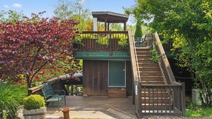 A wooden deck with a green door, a bench, and a small garden area with a potted plant.