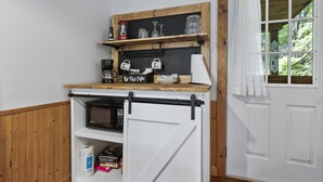 Una cocina con microondas, cafetera y estanterías.
