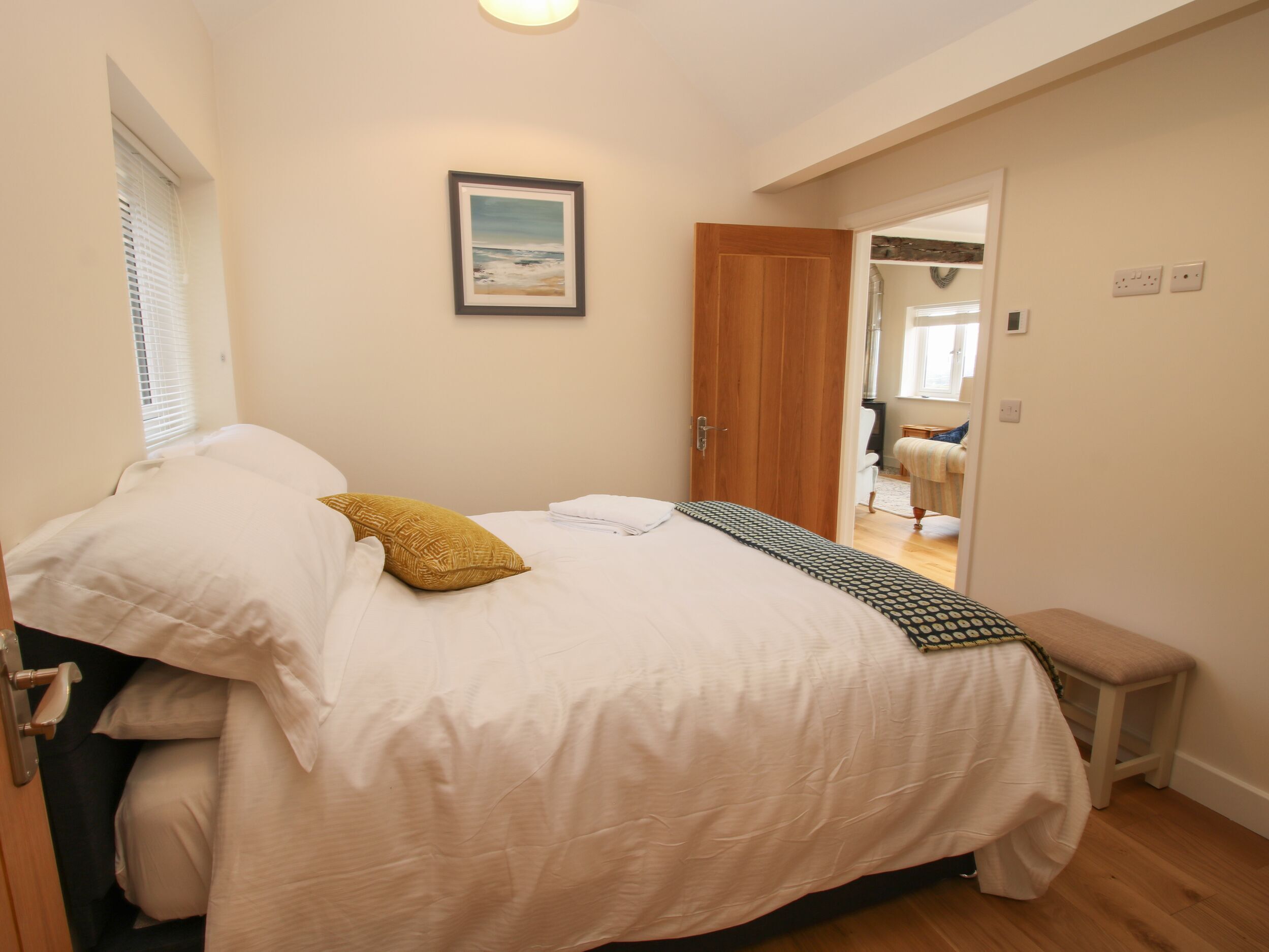 A bedroom with a bed, a bedside table, a mirror, and a door leading to another room.