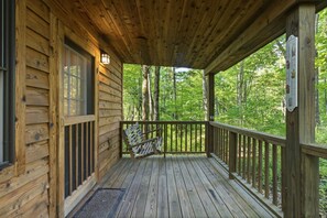A wooden cabin with a porch, a bench, and a thermometer on the wall.