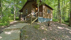 A wooden cabin with a porch and a staircase leading up to the entrance.