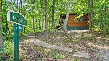 A wooden cabin with a green sign labeled 'Larkspur 2119' in a forested area.