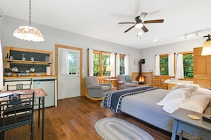 A cozy room with a bed, a rocking chair, a desk, and a fireplace. - Sumac: ADA-Accessible Hocking Hills Cottage with Outdoor Hot Tub & Breakfast (Logan)