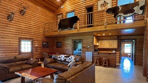 A log cabin interior with a living room, a dining area, and a kitchen. - VTG Lodge  and Guest Suites - Experience the wild frontier of Crockett Texas (crockett)