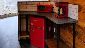 A compact kitchen with a red refrigerator, a microwave, and a coffee maker. - Peridot Geodome: Wooded Hocking Hills Retreat with King Bed, Private Deck and Breakfast (Logan)