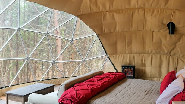 Une pièce aménagée avec une tente, un lit, une table et un ventilateur de plafond.