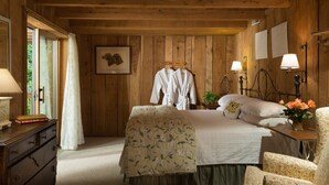 Ein Schlafzimmer mit Holzwandverkleidung, Bett, Nachttischlampen, einem Sessel und einem Schminktisch.