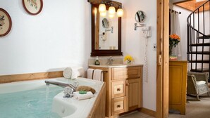 A bathroom with a bathtub, wooden vanity, and a mirror with lights. - Tree House: Romantic Hocking Hills Cabin with King Bed, Soaking Tub and Free Breakfast (Logan)