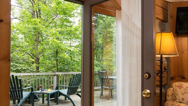 A wooden deck with outdoor furniture, a table, and chairs. - Tree House: Romantic Hocking Hills Cabin with King Bed, Soaking Tub and Free Breakfast (Logan)