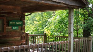 A wooden cabin labeled "Tree House" with a wooden deck and metal chairs. - Tree House: Romantic Hocking Hills Cabin with King Bed, Soaking Tub and Free Breakfast (Logan)