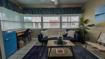 A living room with a sofa, coffee table, and a view of the outside through large windows.