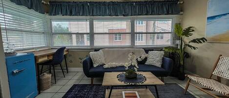 Una sala de estar con sofá, mesa de centro y vistas al exterior a través de amplios ventanales.