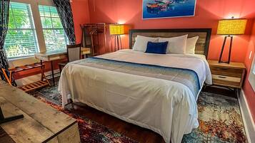 A hotel room with a large bed, two bedside lamps, a ceiling fan, a desk, and a chair.