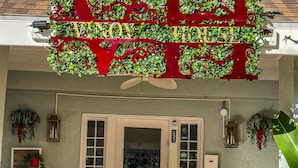 L’entrée d’un hôtel, avec une enseigne rouge et verte, une porte blanche et un banc rouge à l’extérieur.