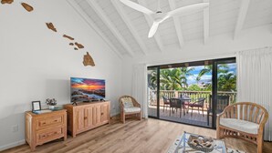 Un amplio salón con un mueble de madera, un televisor y una zona de estar cómoda con vistas al exterior.