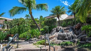 Un resort tropical con una cascada, palmeras y una escalera de piedra que lleva a una zona de observación.
