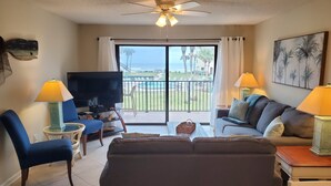 A living room with a TV, two couches, a coffee table, and a ceiling fan. - Summerhouse 433 (St. Augustine)