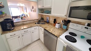 A kitchen with white cabinets, a granite countertop, a coffee maker, a toaster, and a stove. - Summerhouse 433 (St. Augustine)