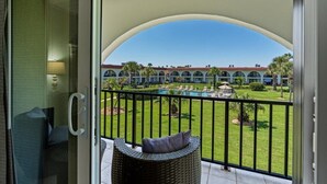 A balcony with a view of a pool and a building with arched windows. - Ocean Club 37 (St. Augustine)