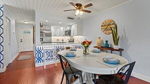 A dining area with a round table, chairs, and a ceiling fan. - Ocean Club 37 (St. Augustine)