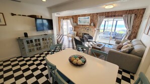A dining area with a checkered floor, a table with chairs, and a television on a cabinet. - Coastal Bliss (St. Augustine)