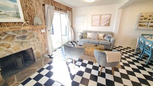 A living room with a stone fireplace, a checkered floor, a grey sofa, and a blue chair. - Coastal Bliss (St. Augustine)