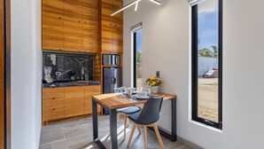 A modern kitchen with wooden cabinets, a built-in refrigerator, and a dining area with a table and chairs. - El Desierto by Naya Homes (San José del Cabo)