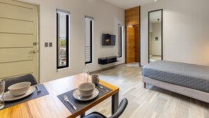 A modern hotel room with a dining area, a bed, a TV, and a large mirror. - El Desierto by Naya Homes (San José del Cabo)