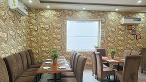Zona pranzo con un tavolo lungo, sedute imbottite e carta da parati decorata.