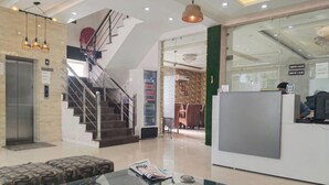 Una hall con una scalinata, una reception e un'area salotto con un tavolo in vetro.