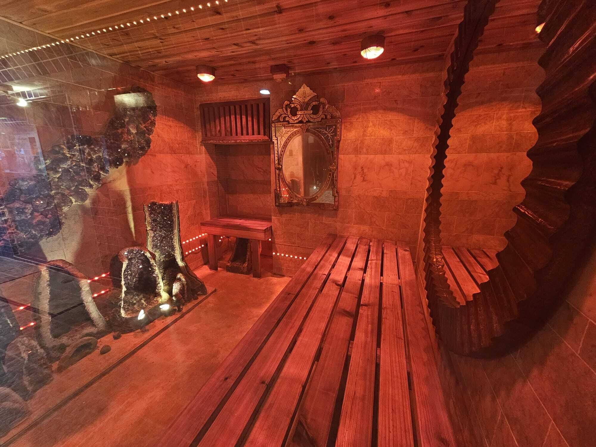 Una stanza con pavimento in legno, una panca, uno specchio e un elemento decorativo a parete.