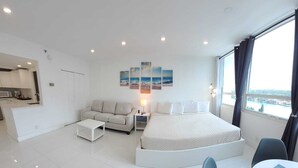 A modern hotel room with a bed, a sofa, a small table, and a view of the city. - OCEANFRONT King Size bed/Bayview with free parking (Miami)