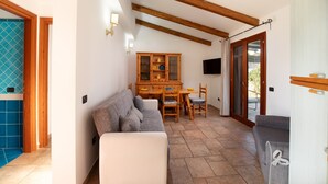 A cozy living room with a sofa, a dining table, and a cabinet. - Casa Carlotta by Wonderful Italy (Loiri Porto San Paolo)