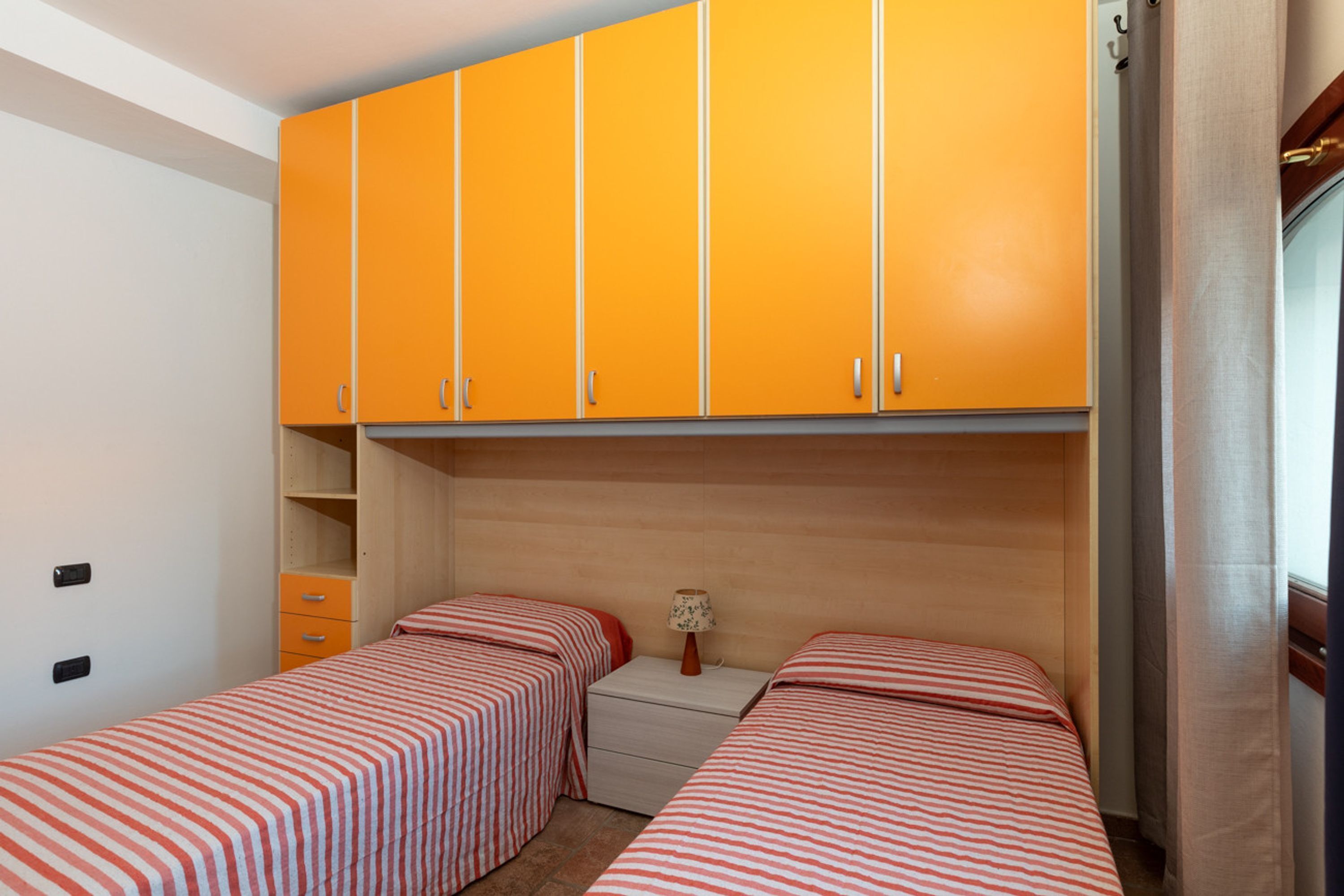 A room with two beds, a small table, and a wardrobe.