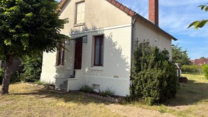 A single-story house with a red-tiled roof, a chimney, and a small porch with steps leading to the entrance. - Maison de Ville Avec Jardin Proche du Pont Canal (Briare)